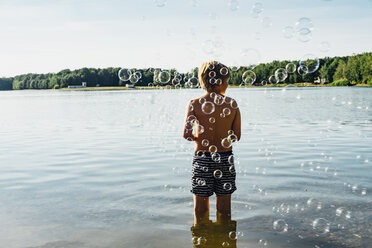Junge in einem See, umgeben von Seifenblasen - MJF02255