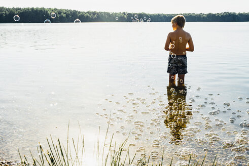 Junge in einem See, umgeben von Seifenblasen - MJF02256