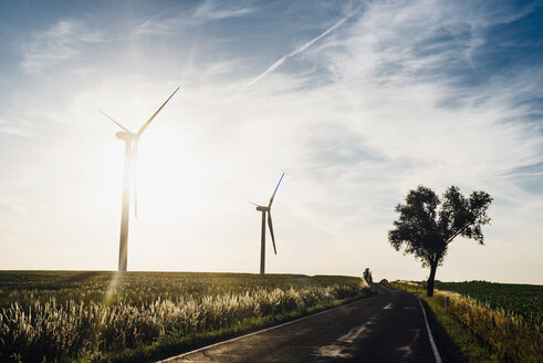 Leere Landstraße und Windräder bei Sonnenuntergang - MJF02267