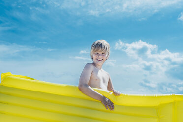 Porträt eines glücklichen Jungen mit einer gelben Luftmatratze im Freien - MJF02280