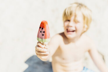 Fröhlicher Junge mit einem Wassermelonen-Eislutscher am Strand - MJF02281