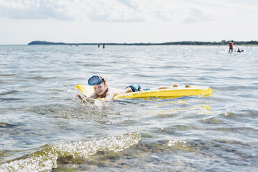 Glücklicher Junge schwimmt auf dem Wasser auf einer Luftmatratze - MJF02282