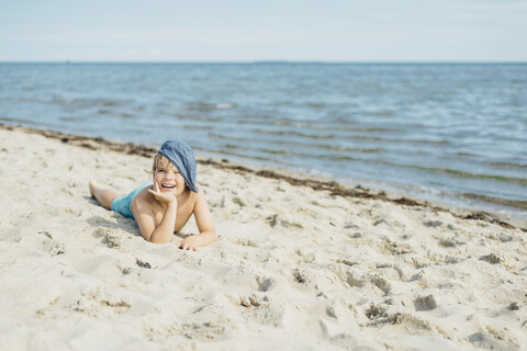 Porträt eines glücklichen Jungen, der am Strand liegt, lizenzfreies Stockfoto