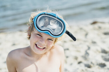 Porträt eines glücklichen Jungen mit Taucherbrille am Strand - MJF02293