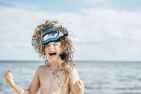 Carefree boy wearing seaweed wig on the beach - MJF02294