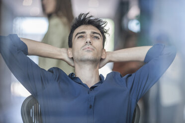 Young businessman sitting with hands behind neck - ISF06400