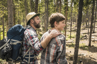 Side view of father with hand on sons shoulder trekking through forest, Red Lodge, Montana, USA - ISF06408