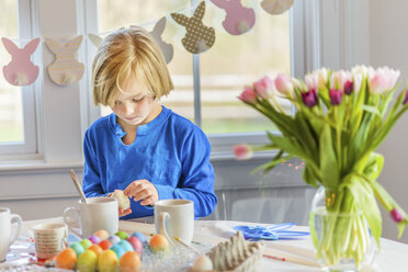 Junge am Tisch, der Eier für Ostern dekoriert - ISF06520