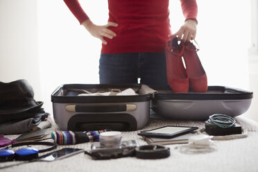 Woman packing suitcase, holding shoes, mid section - ISF06564