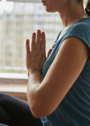 Abgeschnittene Seitenansicht einer Frau, die ihre Hände zum Meditieren zusammenlegt - ISF06581