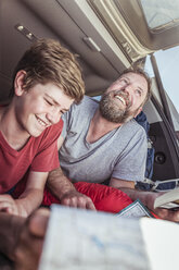 Älterer Mann und Sohn im Teenageralter lesen Karte, während sie im Fahrzeug liegen - CUF17415