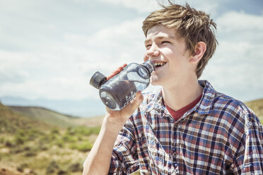 Jugendlicher in einer Landschaft, der Wasser in Flaschen trinkt, Bridger, Montana, USA - CUF17428