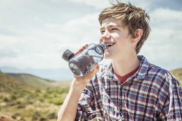 Teenage boy in landscape drinking bottled water, Bridger, Montana, USA - CUF17428