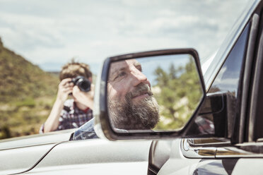 Teenage boy photographing father in off road vehicle, Bridger, Montana, USA - CUF17429