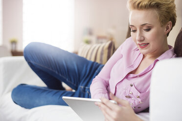 Woman using digital tablet on sofa - CUF17464