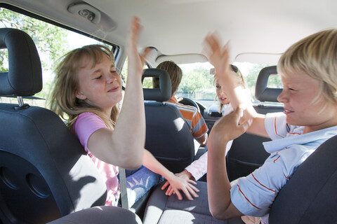 Children fighting in back seat of vehicle on road trip stock photo