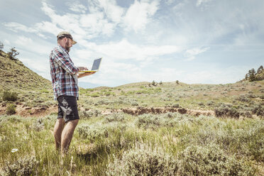 Man typing on laptop selfie in landscape, Bridger, Montana, USA - CUF17501