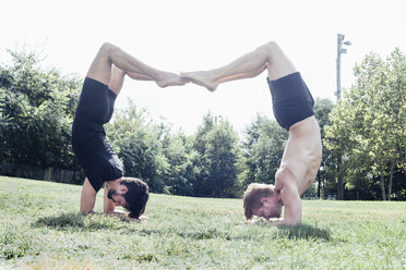 Zwei Männer in Yoga-Stellung im Park auf dem Kopf stehend - ISF06593