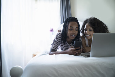 Lesbisches Paar auf dem Bett liegend, mit Laptop - ISF06595