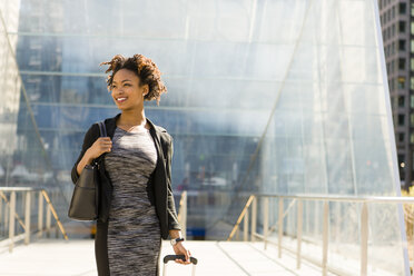 Businesswoman outdoors, pulling wheeled suitcase - ISF06607