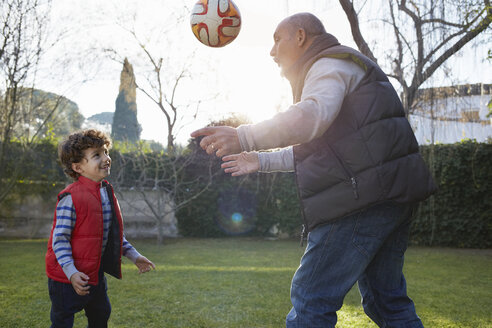 Großvater und Enkel spielen lächelnd mit einem Fußball - CUF17669