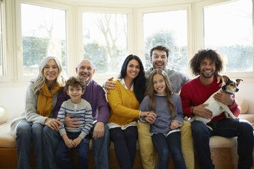 Multi generation family and dog on window seat looking at camera smiling - CUF17683