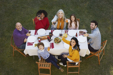 Overhead view of multi generation family dining outdoors looking up at camera, making a toast smiling - CUF17689