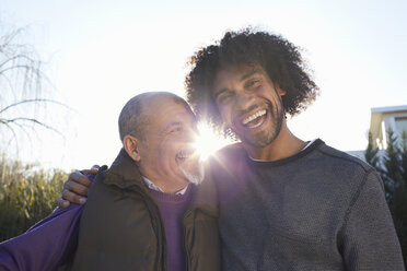 Men with arms around each other smiling in sunlight - CUF17692