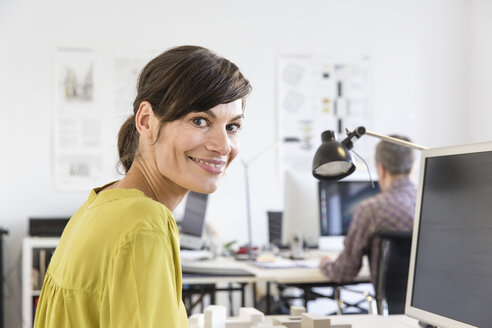 Side view of mature woman in office looking at camera smiling - CUF17728