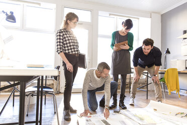 Architects discussing blueprint on office floor - CUF17740