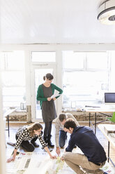 High angle view of architects on office floor discussing blueprint - CUF17745