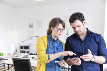 Kollegen im Büro, die nach unten schauen und über Smartphones diskutieren - CUF17752