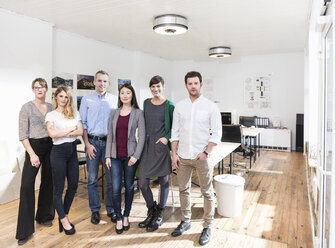 Full length view of colleagues side by side in office looking at camera smiling - CUF17768