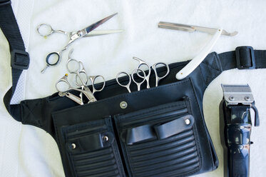 Overhead view of hairdressers tool belt with scissors, hair clippers and straight razor - CUF17859
