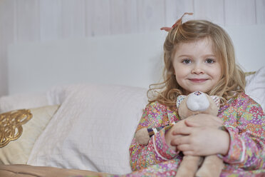 Girl in pyjamas hugging teddy bear in bed - CUF17899