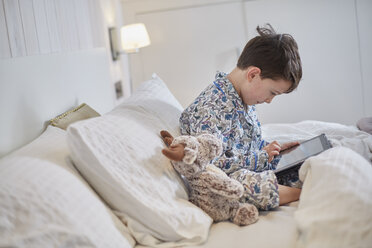 Junge im Schlafanzug mit digitalem Tablet im Bett - CUF17900