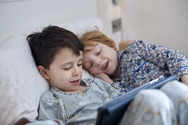 Jungen im Schlafanzug mit digitalem Tablet im Bett - CUF17905