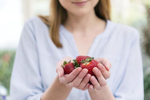 Frau mit schalenförmigen Händen, die Erdbeeren halten, lizenzfreies Stockfoto