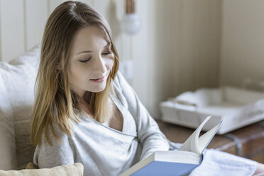 Woman sitting on bed reading book - CUF17943