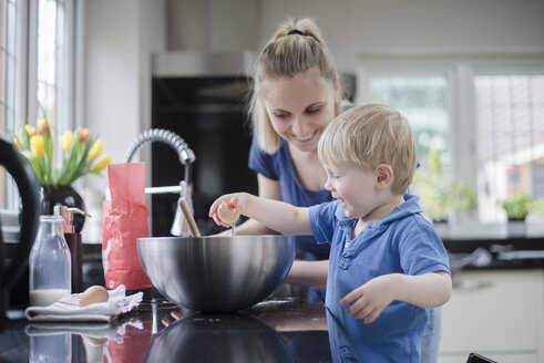 Mutter hilft Sohn beim Backen eines Kuchens, Sohn schlägt ein Ei auf - CUF17948