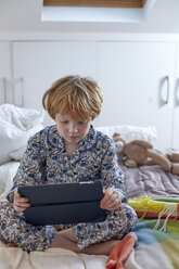 Junge im Schlafanzug mit digitalem Tablet im Bett - CUF17976