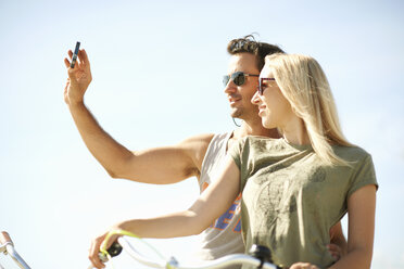 Radfahrendes Paar macht ein Smartphone-Selfie am Venice Beach, Los Angeles, Kalifornien, USA - ISF06657