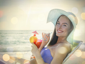 Porträt einer jungen Frau auf einem Liegestuhl sitzend mit einem Cocktail am Strand von Miami, Florida, USA - ISF06660