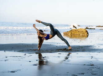 Junge Tänzerin balanciert auf einer Hand am Strand, Los Angeles, Kalifornien, USA - ISF06705