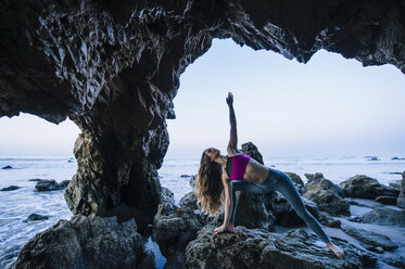 Junge Tänzerin balanciert auf einer Hand in einer Meereshöhle, Los Angeles, Kalifornien, USA - ISF06706