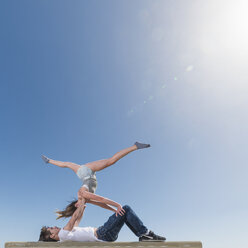 Paar übt Partner-Yoga auf einer Bank - ISF06713