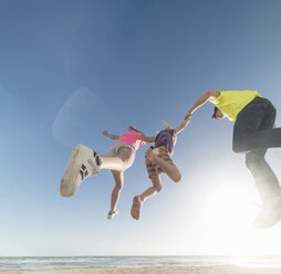 Freunde springen mitten in der Luft übers Meer - ISF06715