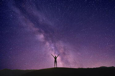 Person stretching arms in front of aurora, Death Valley, California, USA - ISF06732