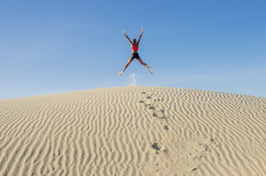 Runner jumping up with arms and legs outstretched in desert, Death Valley, California, USA - ISF06734