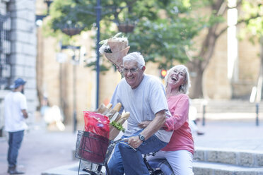 Älterer Mann und Frau mit Blumenstrauß beim Radfahren in der Stadt - ISF06748